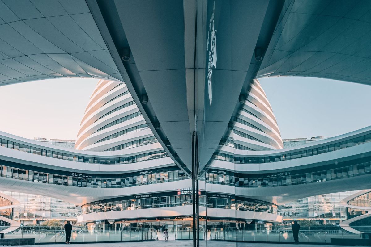 Façade architecturale moderne aux formes ondulantes reflétées dans une surface brillante
