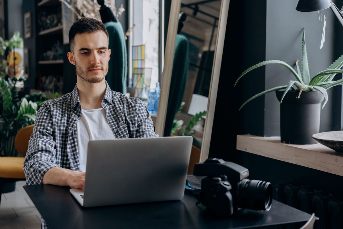 Homme en chemise à carreaux travaillant sur son ordinateur portable dans un bureau moderne