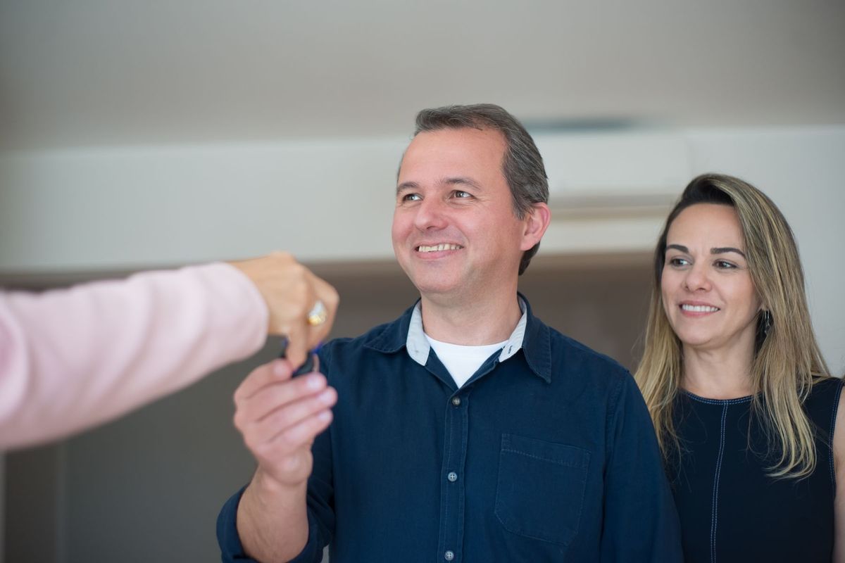 Couple heureux recevant les clés de sa nouvelle maison lors de la signature de l'acte d'achat