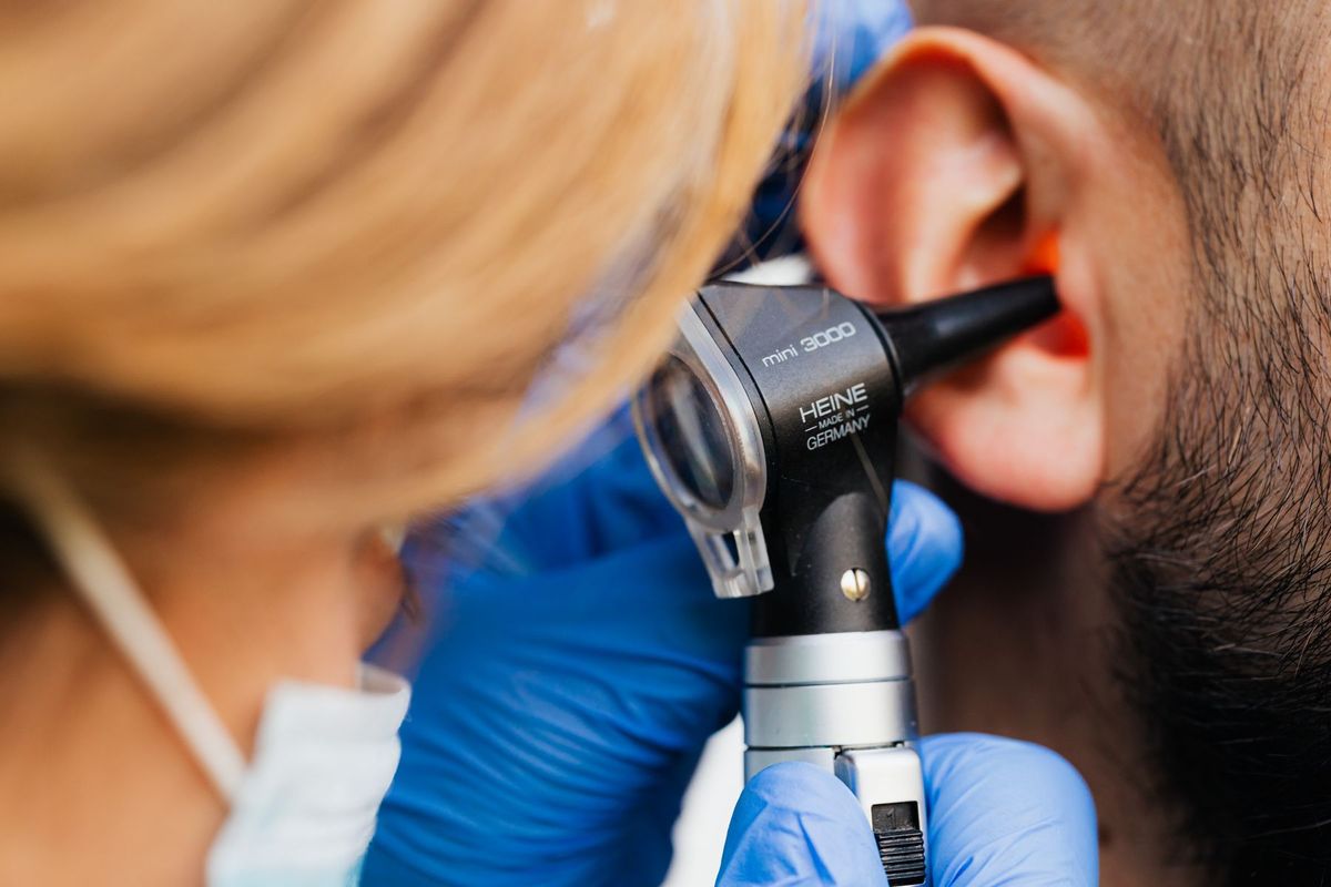 Médecin ORL examinant l'oreille d'un patient avec un otoscope