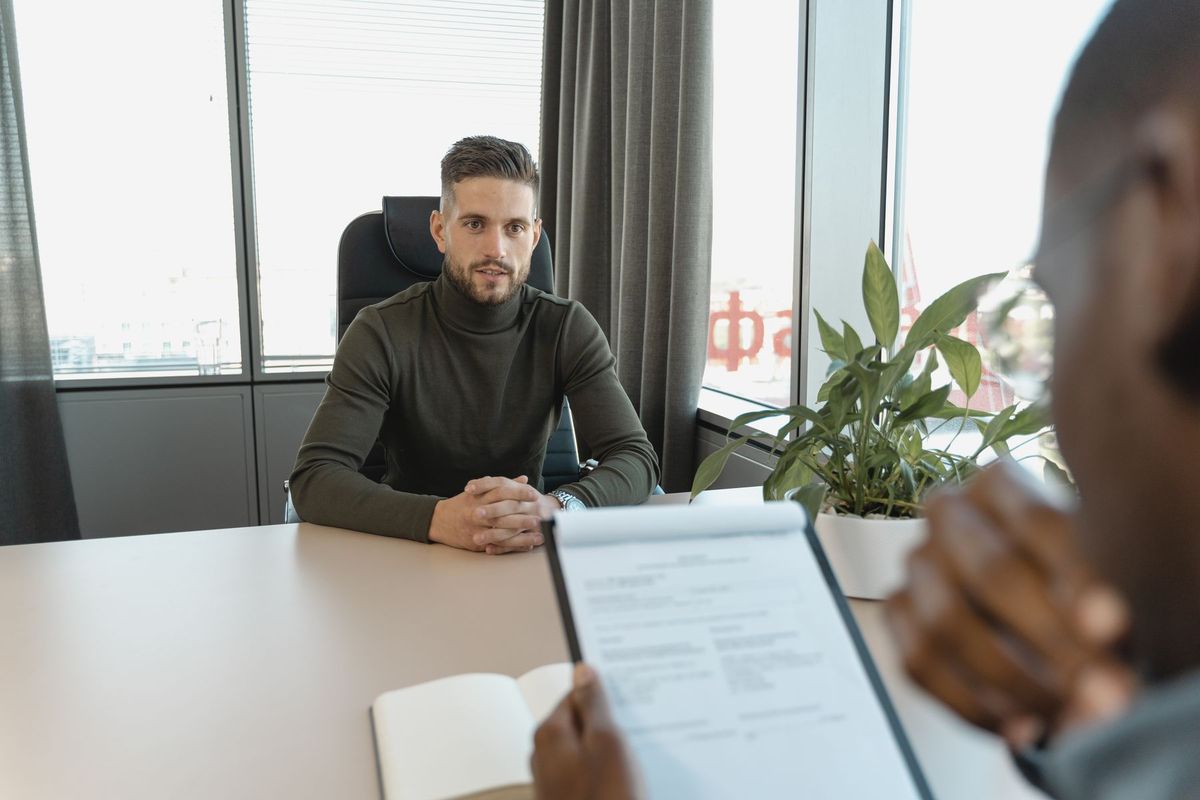 Professionnel en col roulé conduisant un entretien d'embauche à son bureau