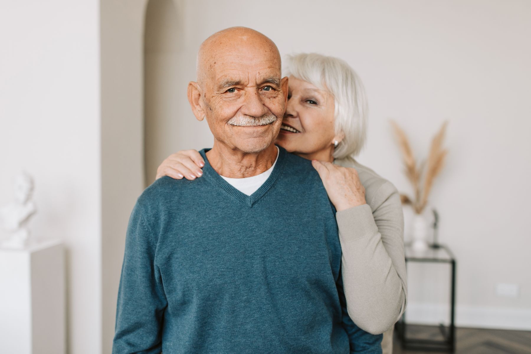 Couple de retraités souriants s'embrassant dans un intérieur chaleureux, symbolisant la sérénité financière