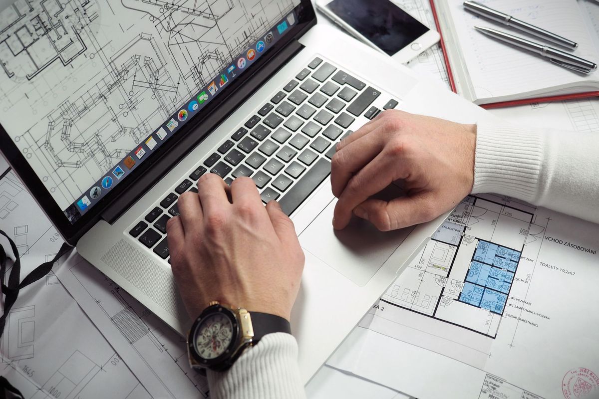 Architecte consultant des plans détaillés sur son ordinateur portable au bureau