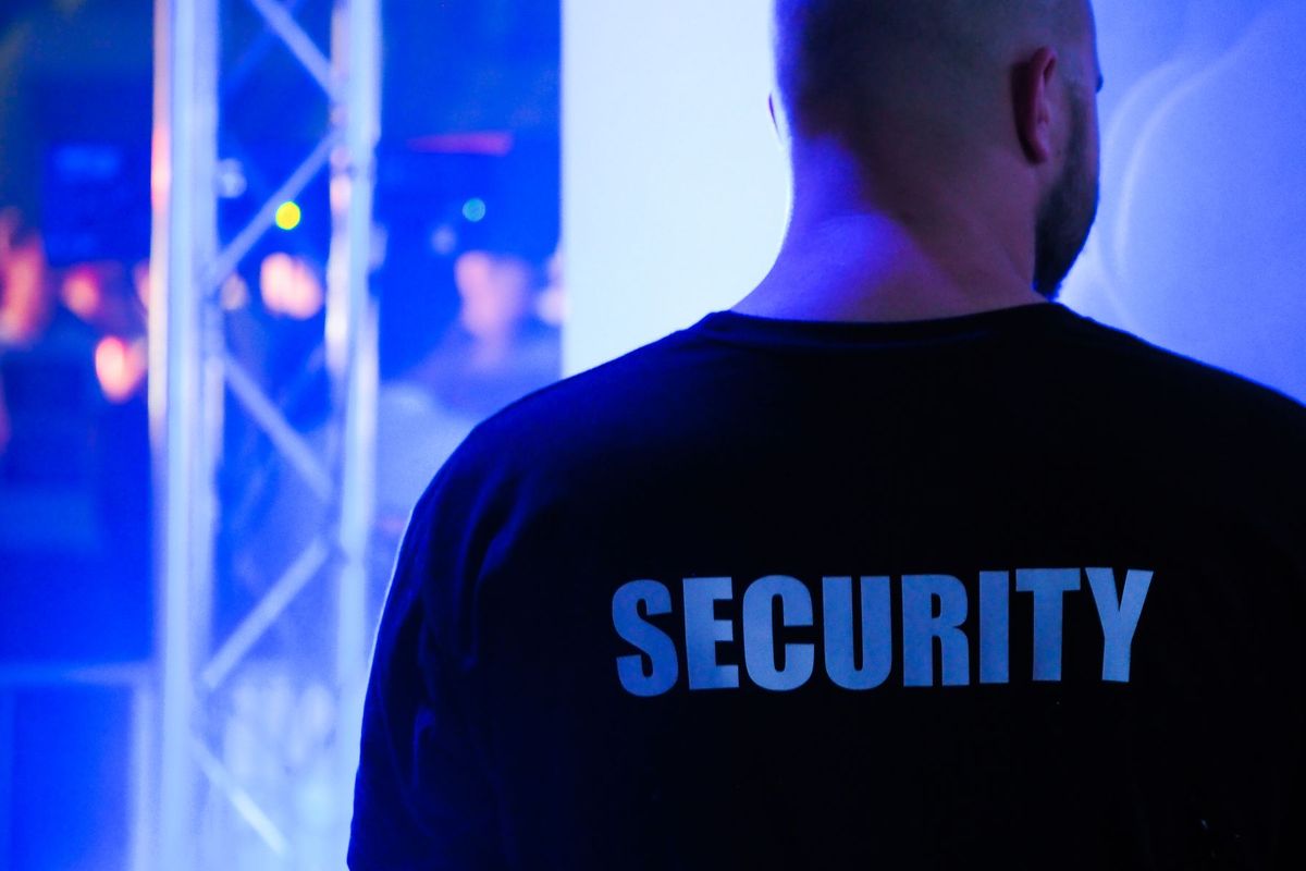 Agent de sécurité en uniforme noir surveillant l'accès dans une discothèque