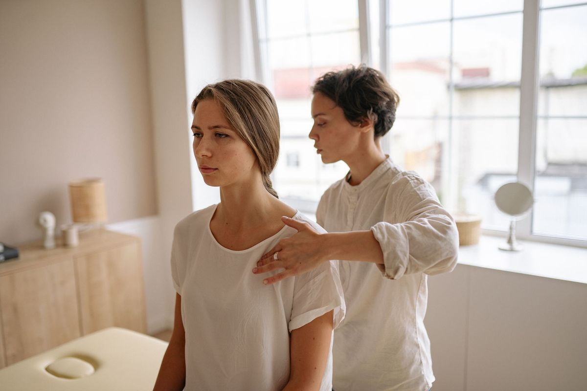 Thérapeute en shiatsu massant les épaules d'une cliente dans un cadre zen et lumineux