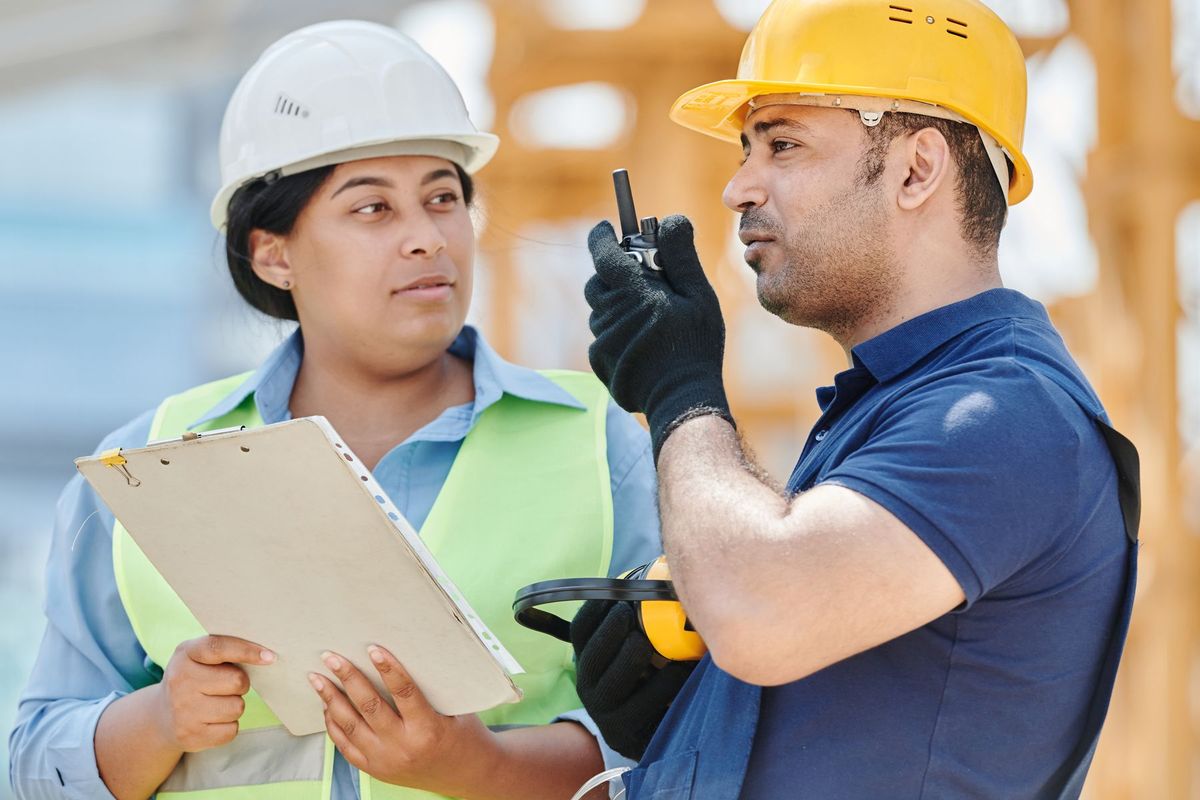 Deux coordinateurs en équipement de sécurité examinent les plans de chantier ensemble