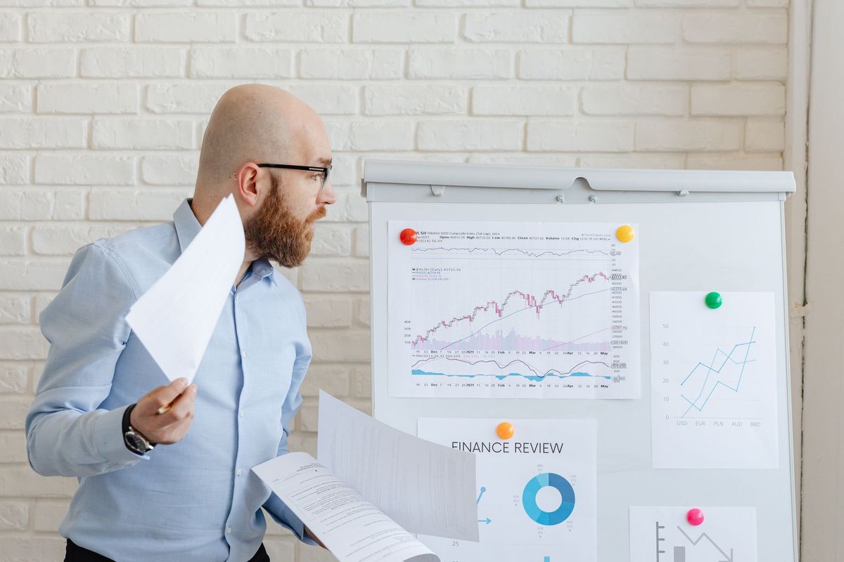 Homme d'affaires analysant des graphiques financiers sur un tableau blanc en bureau