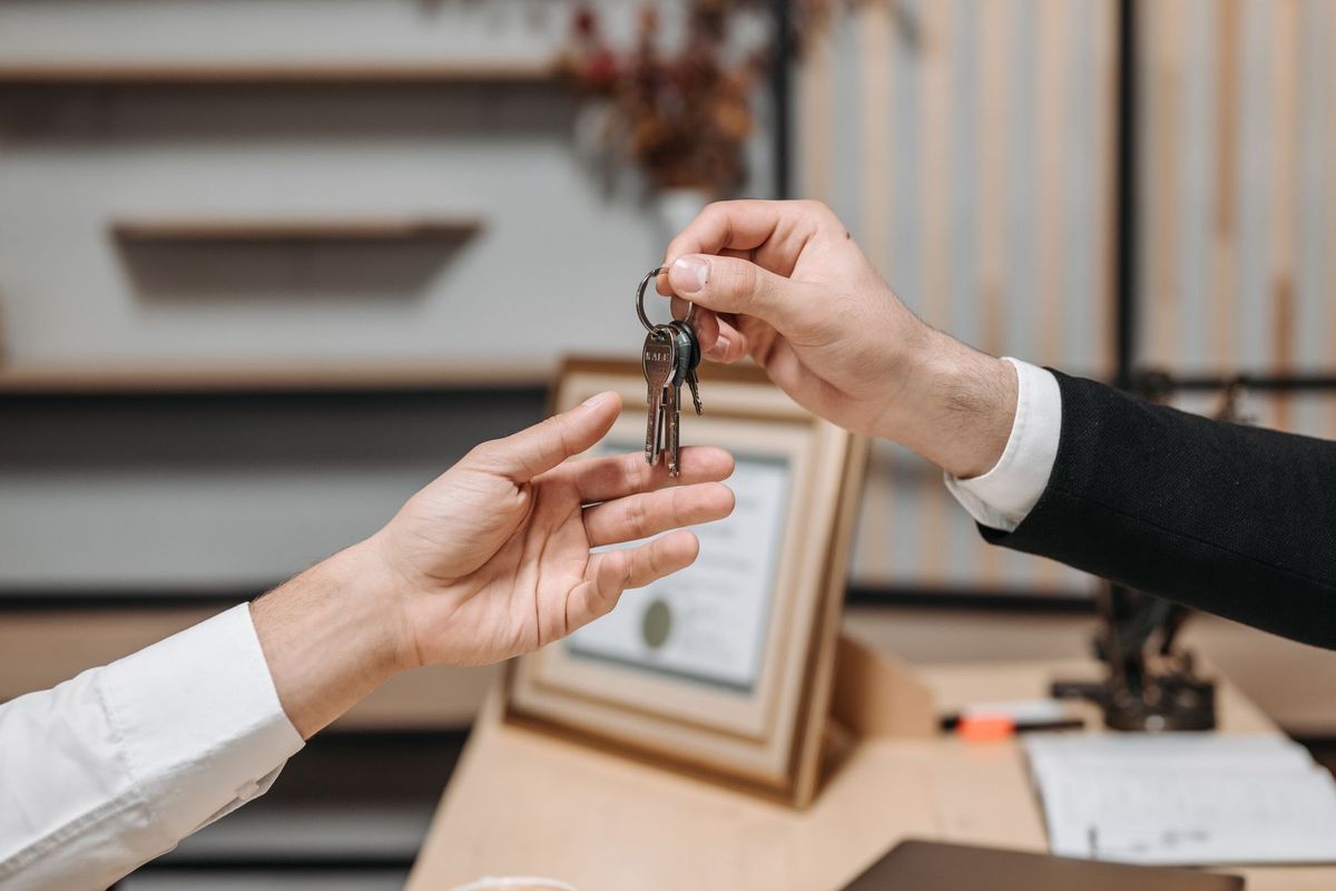 Deux mains se serrent en échangeant les clés d'un bien immobilier dans un bureau professionnel