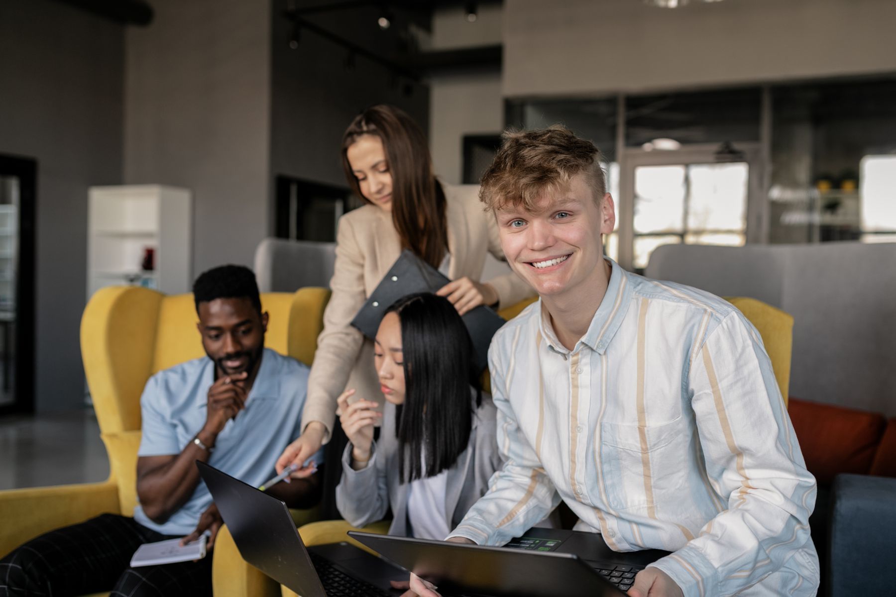 Équipe de collaborateurs réunis autour de leurs ordinateurs portables dans un espace de travail contemporain