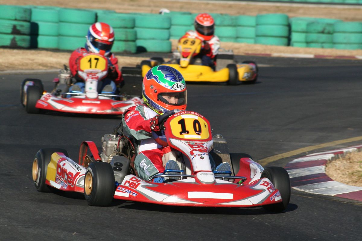 Trois pilotes de karting se disputent la première place sur un circuit ensoleillé