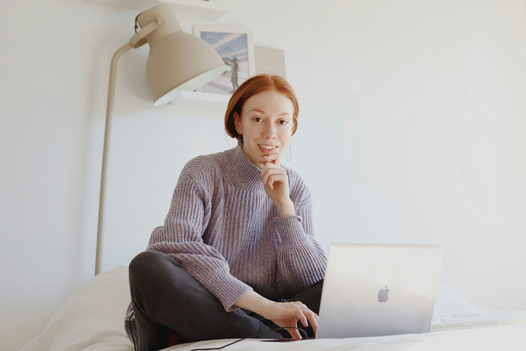 Femme en pull gris assise sur une chaise travaillant sur son ordinateur portable