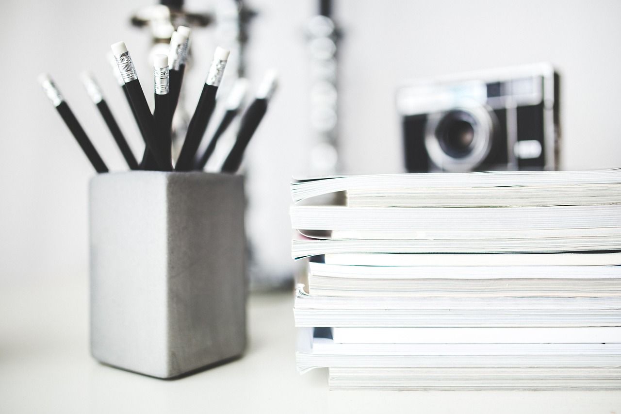 Crayons et cahiers empilés sur un bureau de travail en noir et blanc
