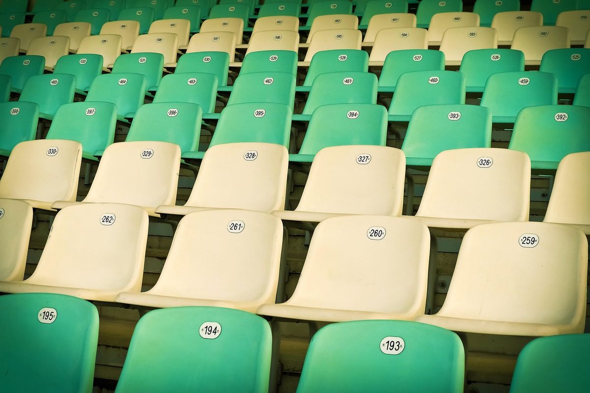 Rangées de sièges en plastique numérotés dans un stade, illustrant la production industrielle
