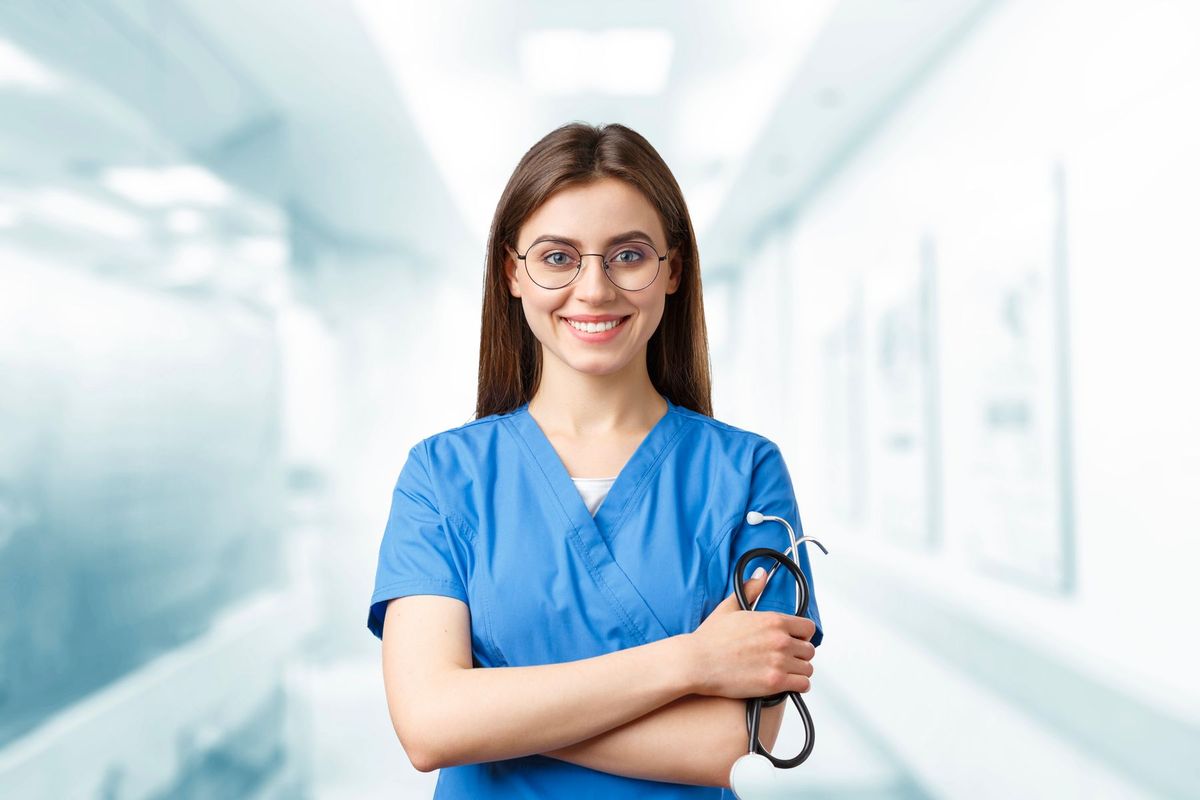 Infirmière en blouse bleue avec stéthoscope dans un couloir d'établissement de santé