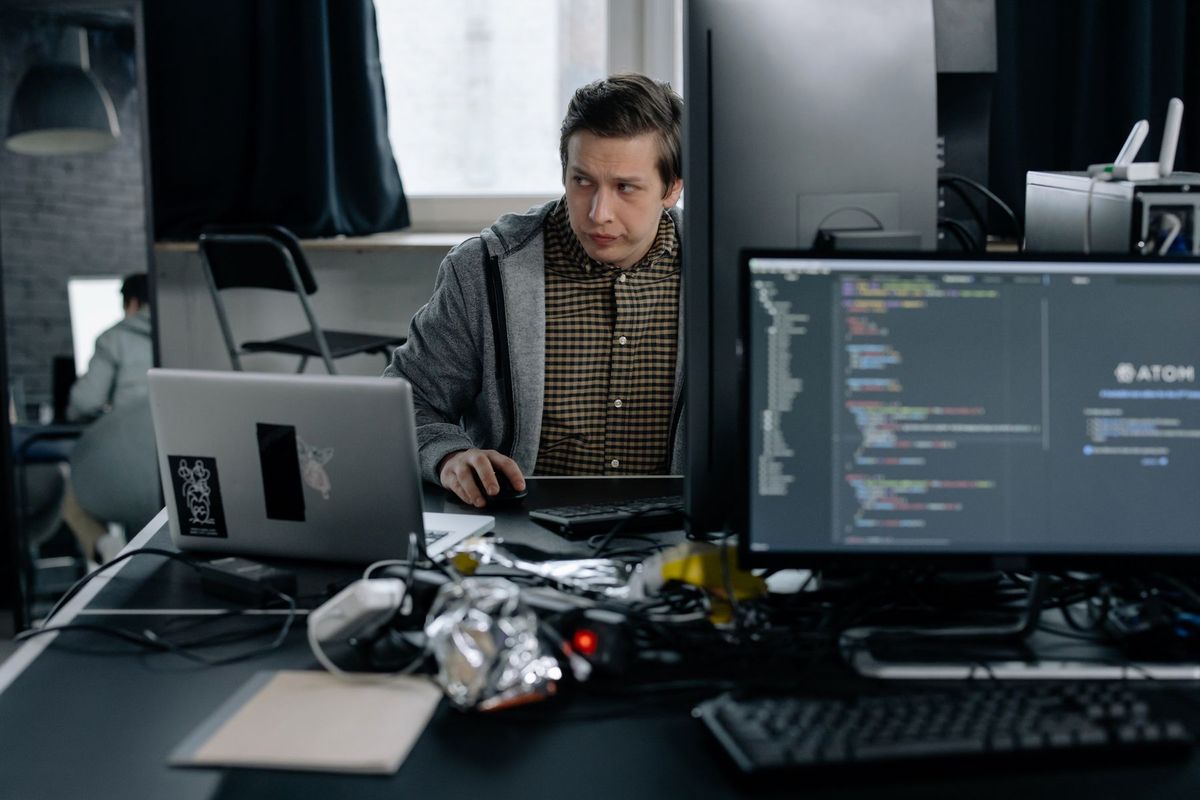 Développeur concentré sur son écran affichant du code source en environnement de bureau professionnel