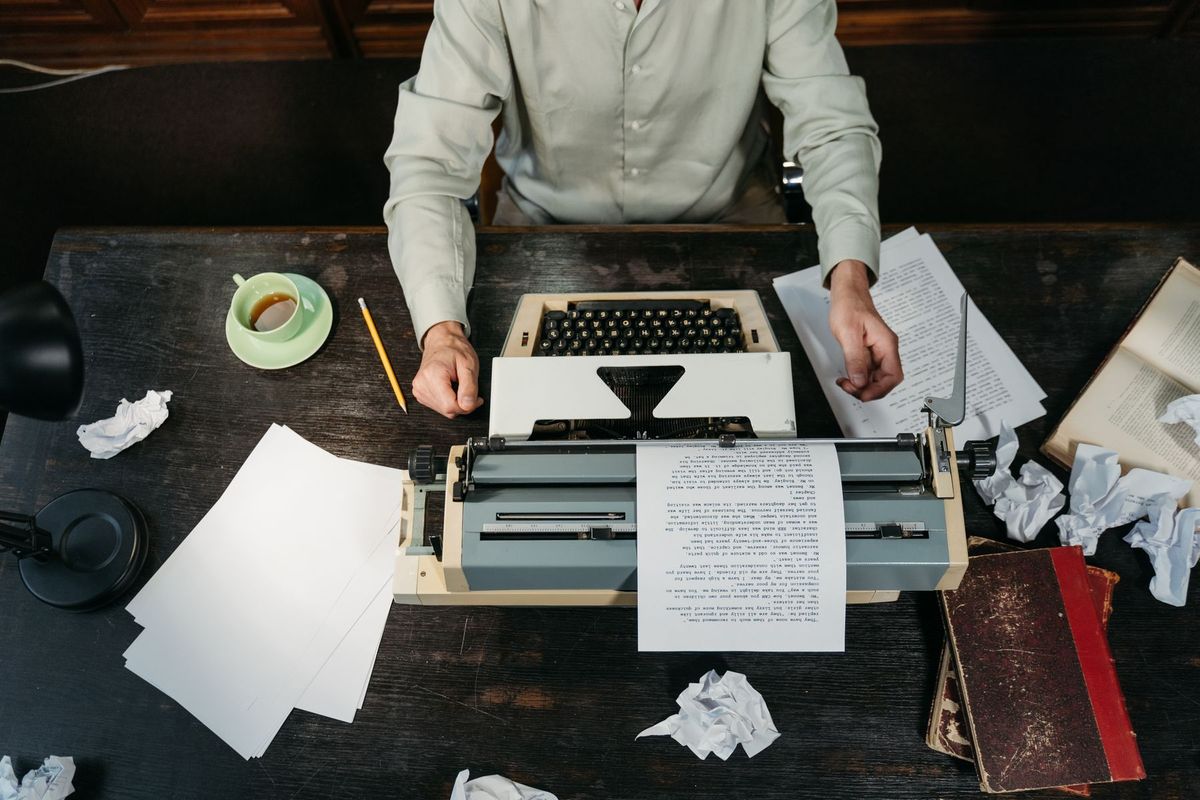 Écrivain assis à son bureau avec machine à écrire vintage, papiers et notes dispersés autour