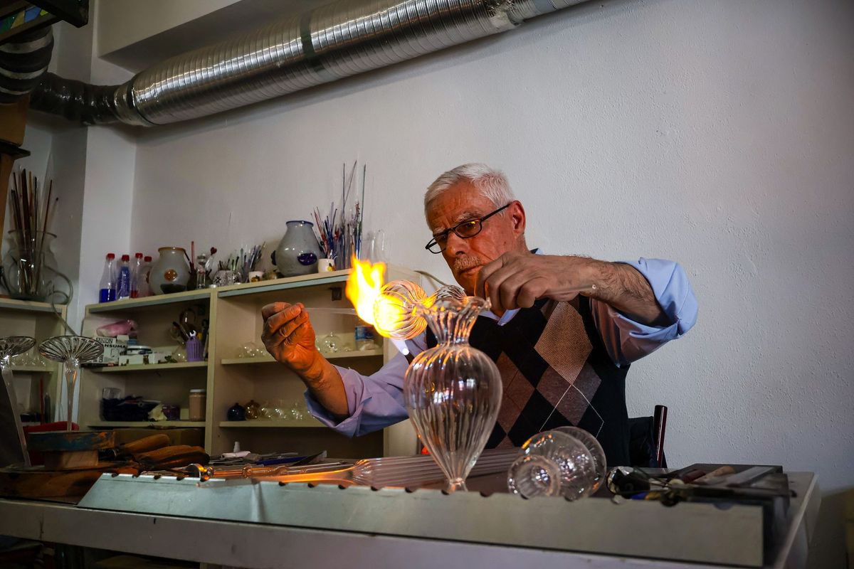 Artisan verrier concentré façonnant une pièce de verre incandescente à l'aide de ses outils