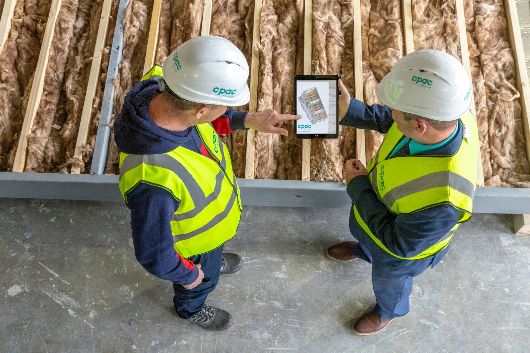 Deux ouvriers du bâtiment consultent les plans de chantier sur une tablette
