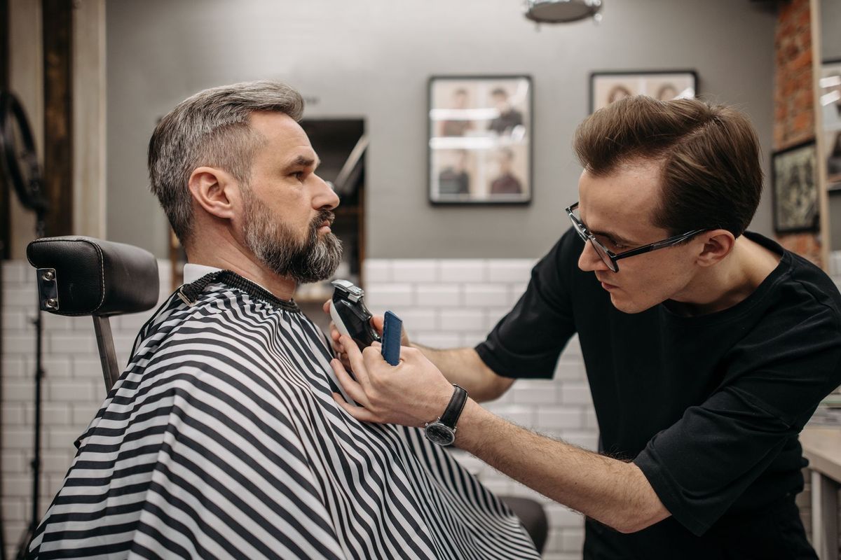 Barbier concentré taillant précisément la barbe d'un client dans un barbershop moderne