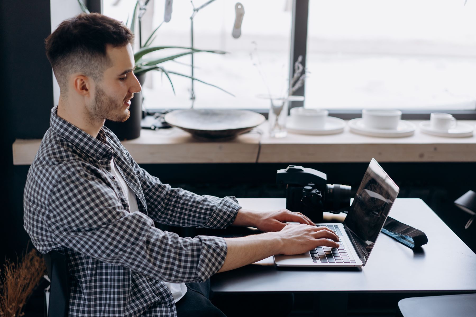 Jeune professionnel indépendant travaillant sur son ordinateur portable avec appareil photo