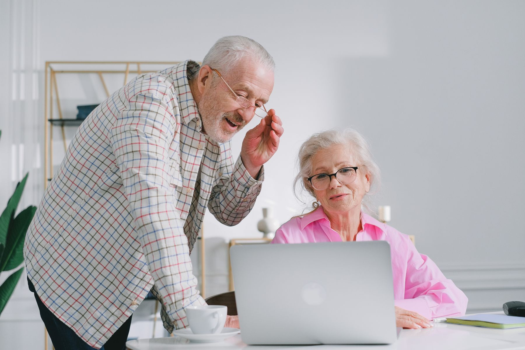 Couple de retraités discutant devant un ordinateur portable dans un salon lumineux