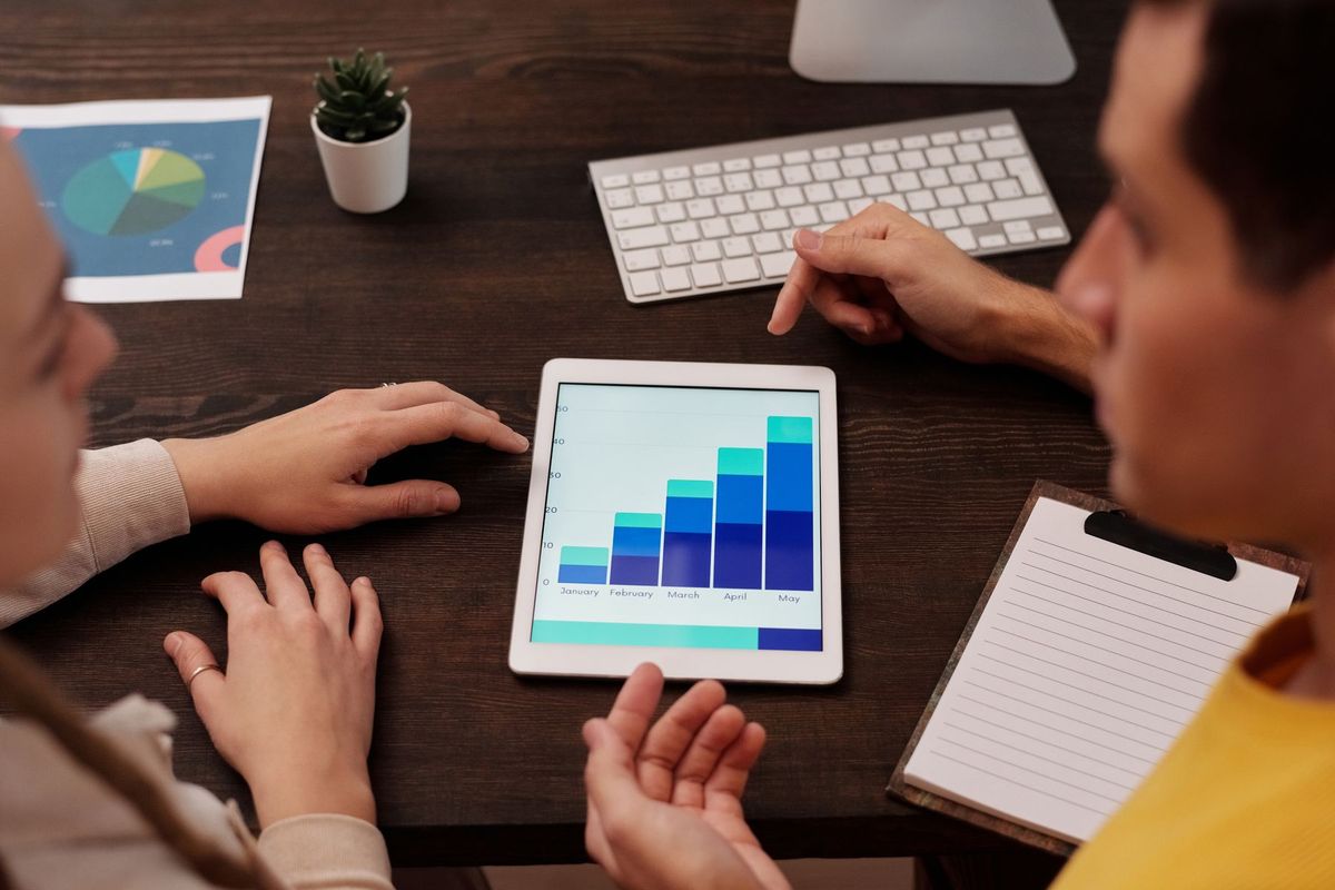 Consultant SEO analysant des graphiques de performance sur tablette avec son équipe en réunion