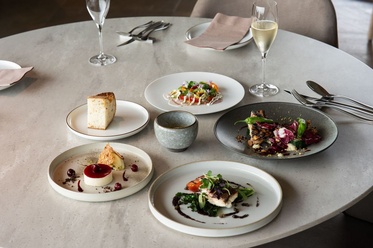 Chef en toque blanche présentant un plat raffiné dans une cuisine gastronomique