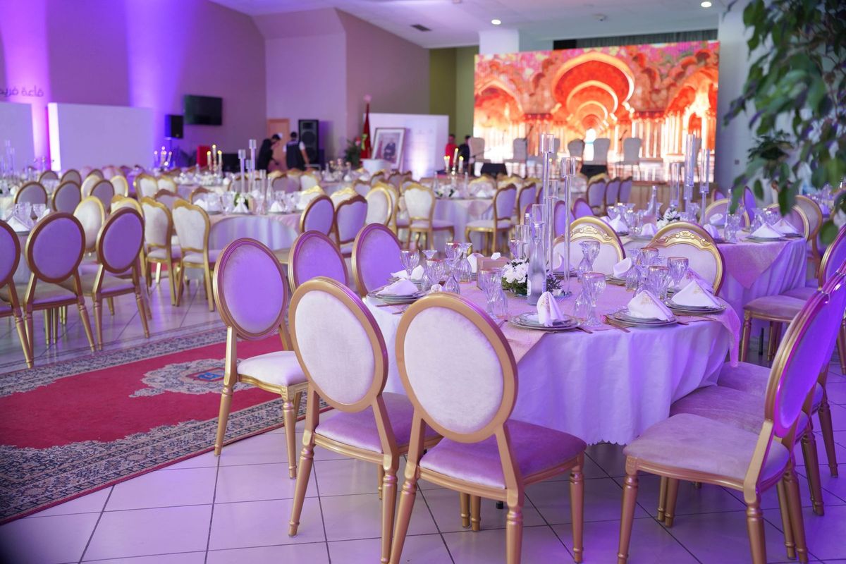 Salle de banquet élégamment décorée avec tables dressées et éclairage violet pour un événement de prestige