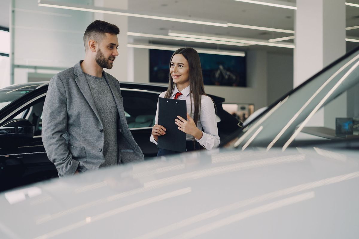 Un vendeur discute avec un client dans un showroom automobile moderne