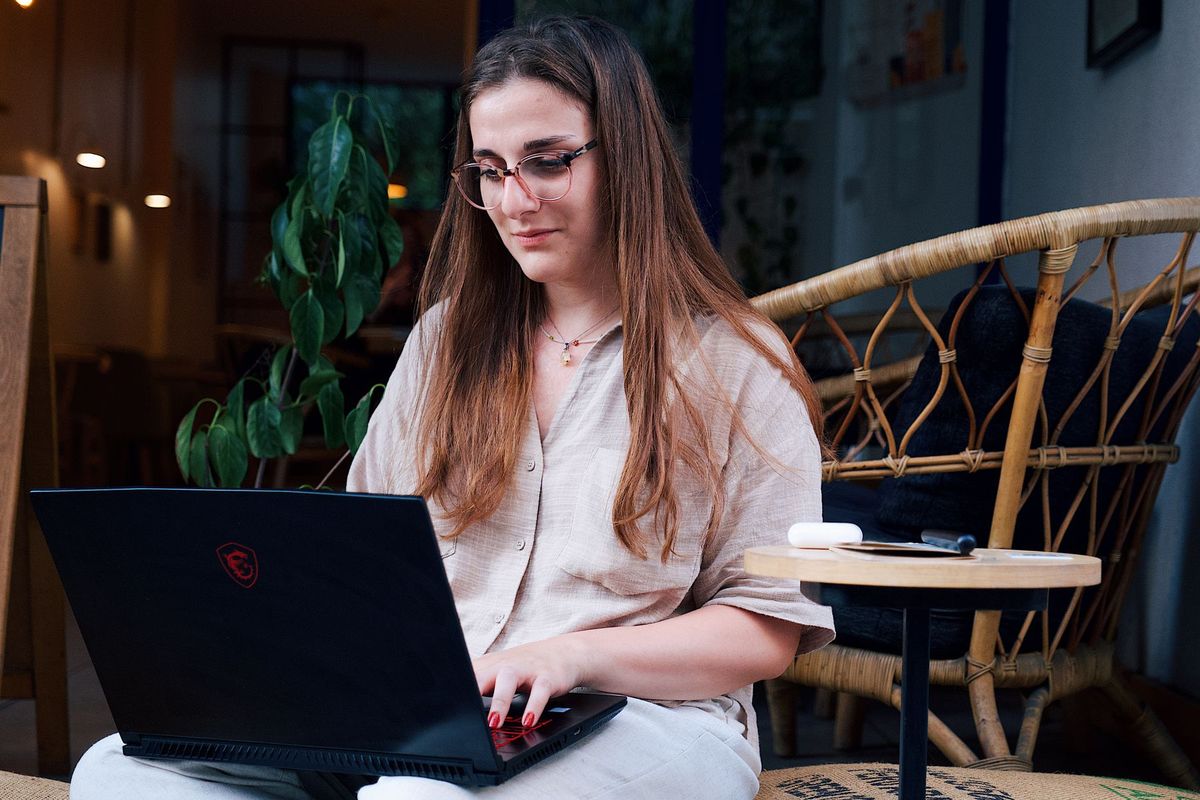 Femme avec lunettes travaillant sur son ordinateur portable dans un café, concentrée sur ses tâches