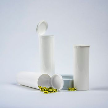 three white 60 dram pop-top bottles with gel capsules spilling out of one on its side