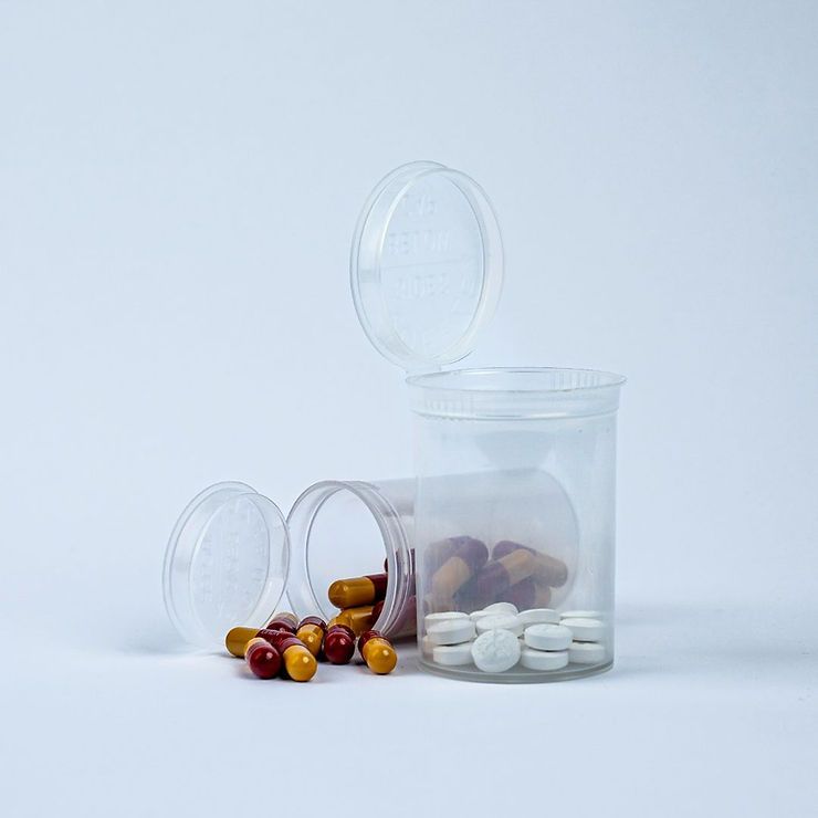 two clear pop-top pill bottles filled with prescription medications