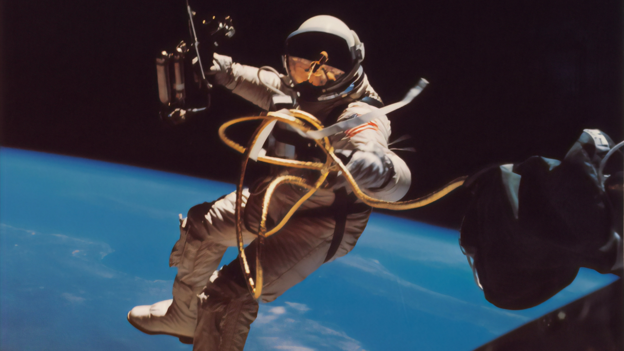 An astronaut (trained with the positive psychology technique of 'practice stress' so that he can perform at his best even under extreme conditions like those in space) floats in his white space suit above the Earth in the distance.