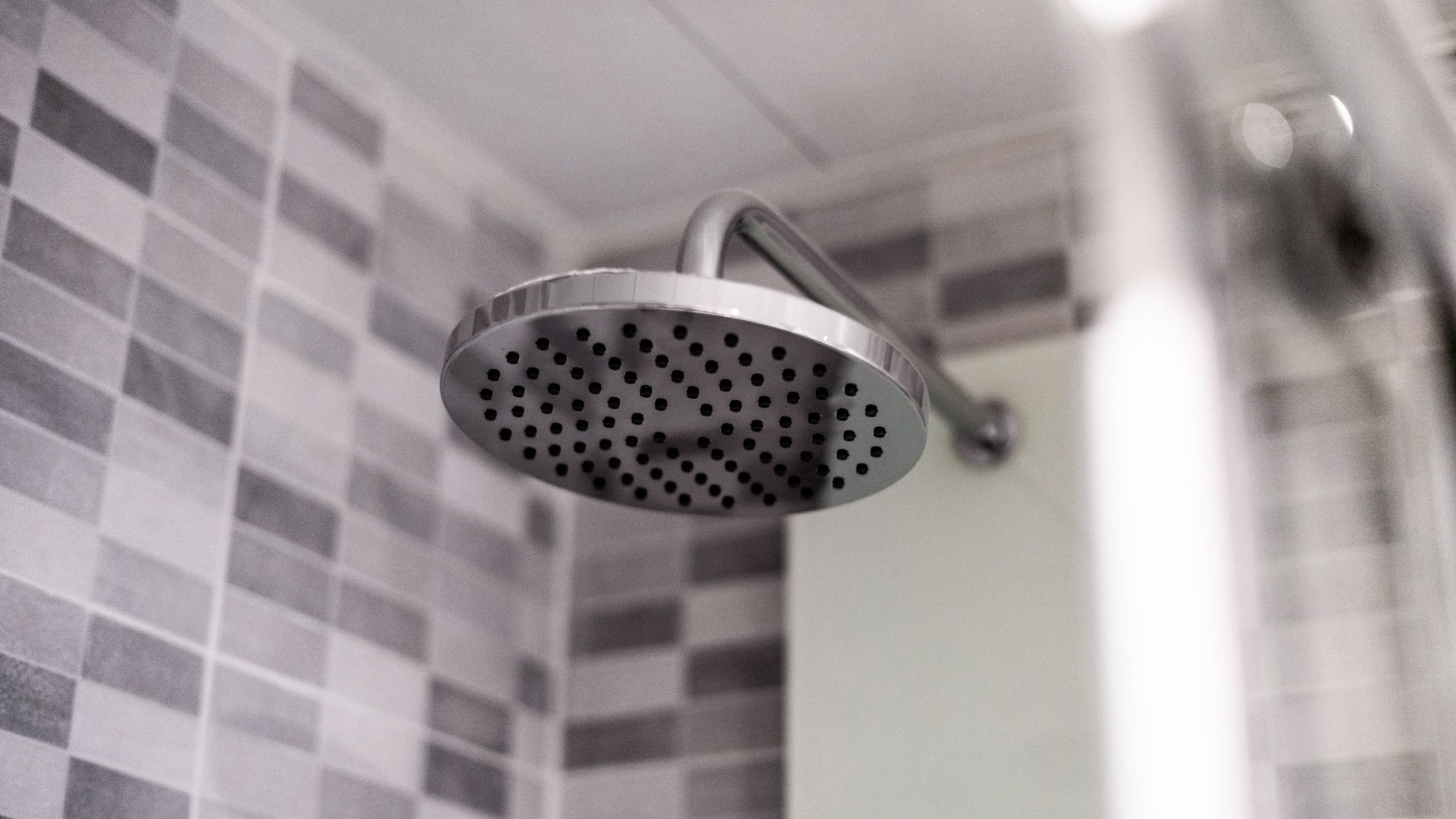 A black and white image of a dripping shower head to illustrate that a cold shower can help wake you up after a poor night's sleep 