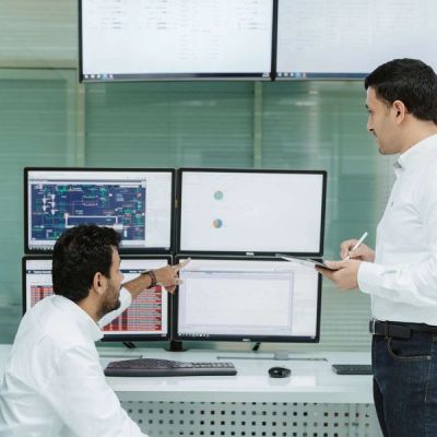 2 people discussing data on monitors