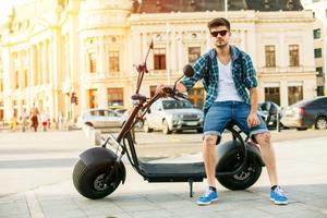 Man sitting on electric scooter in city center