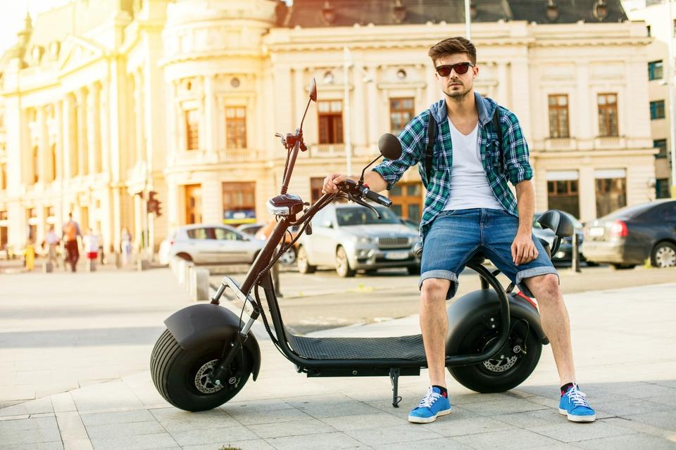 Man sitting on electric scooter in city center