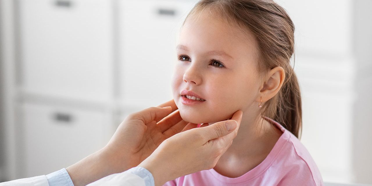 Médico examinando a tireoide de uma criança, ilustrando cuidados com a saúde infantil e diagnóstico de disfunções da tireoide