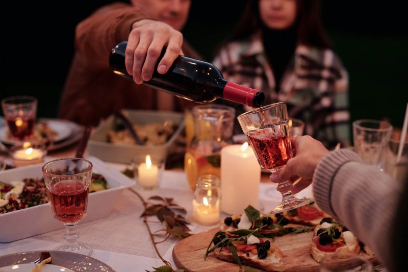 A person pouring wine into someone else's cup while dining outdoors