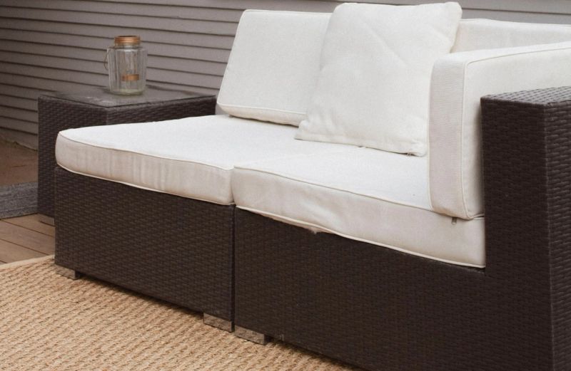 Rattan sofa outdoors with white cushions