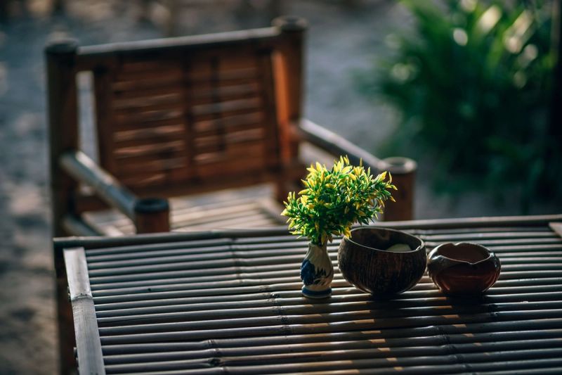 Close up of a wooden table with some bowls and plants, and a wooden chair in the background