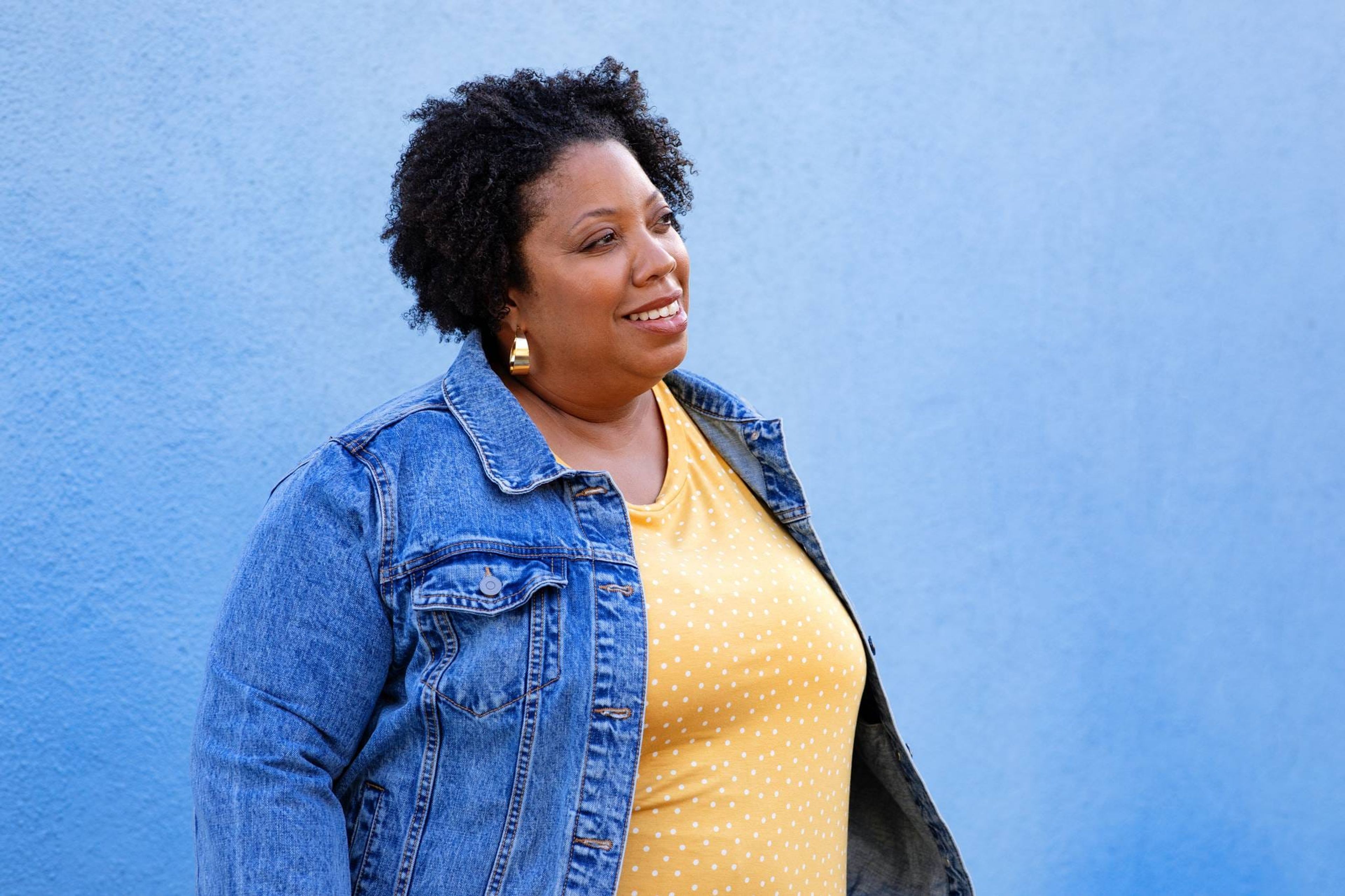 Woman in a denim jacket against a blue wall