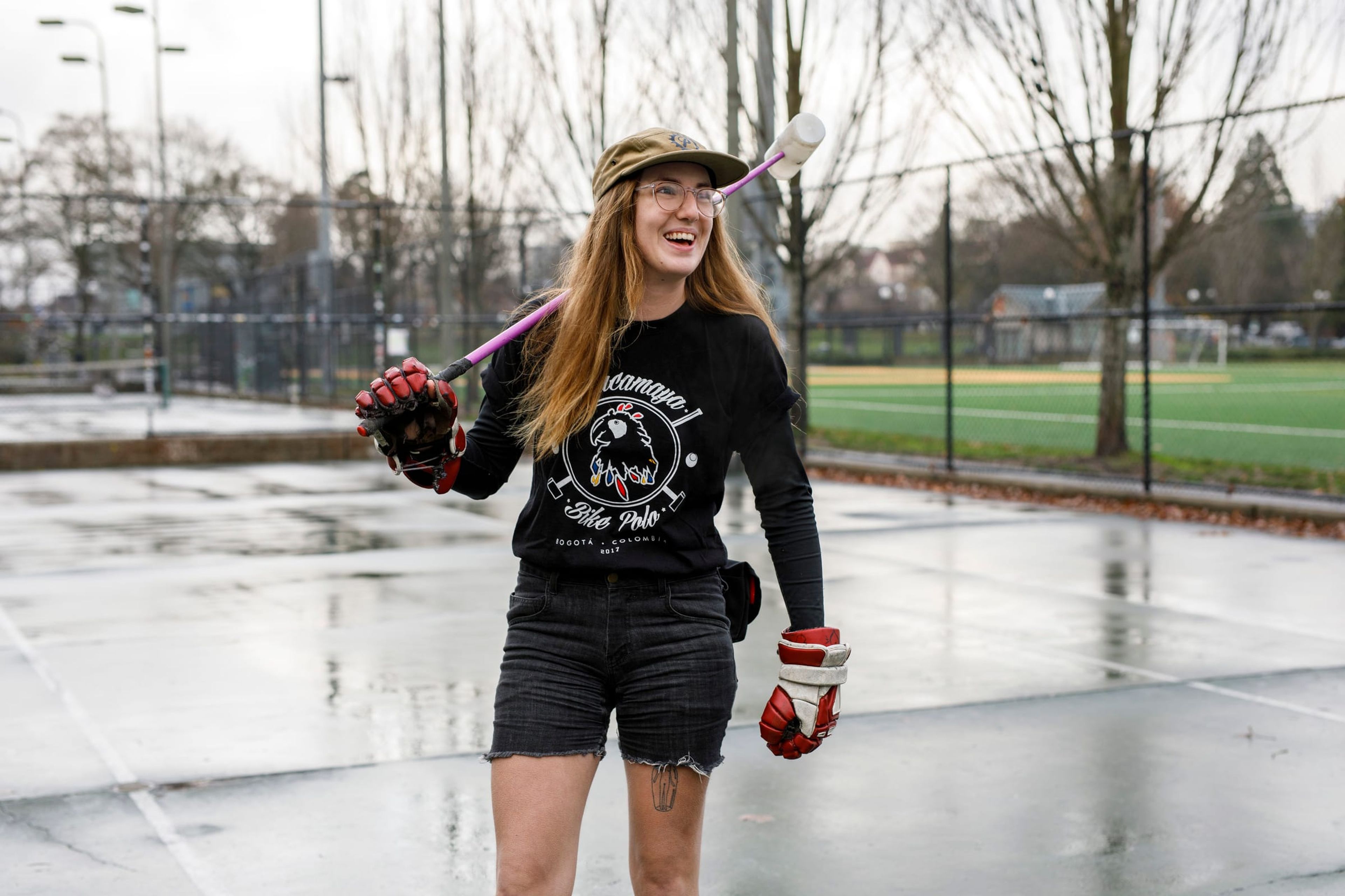 Woman holding a bike polo mallet on a wet court