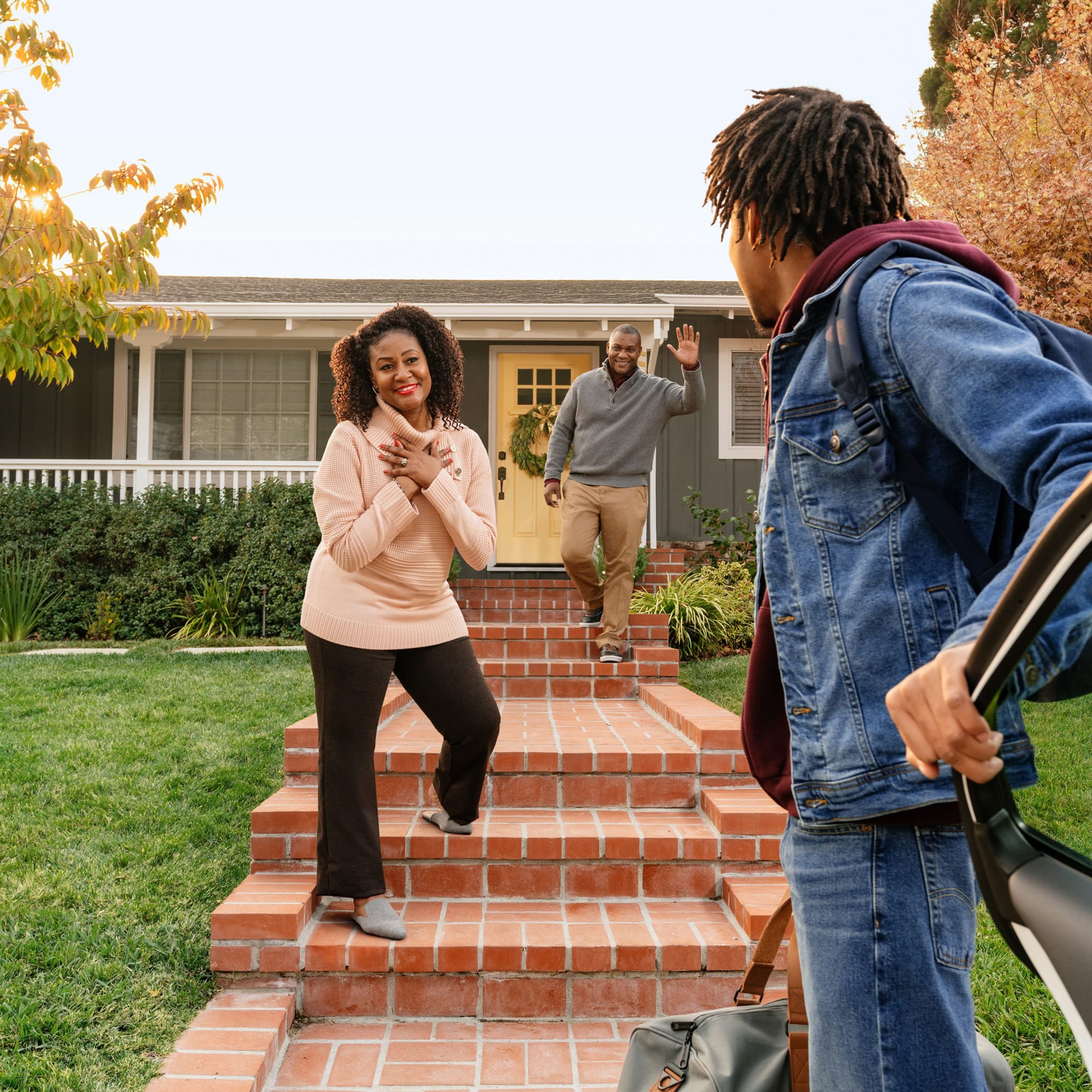 Man stepping out of a car as friends wave from a front stoop