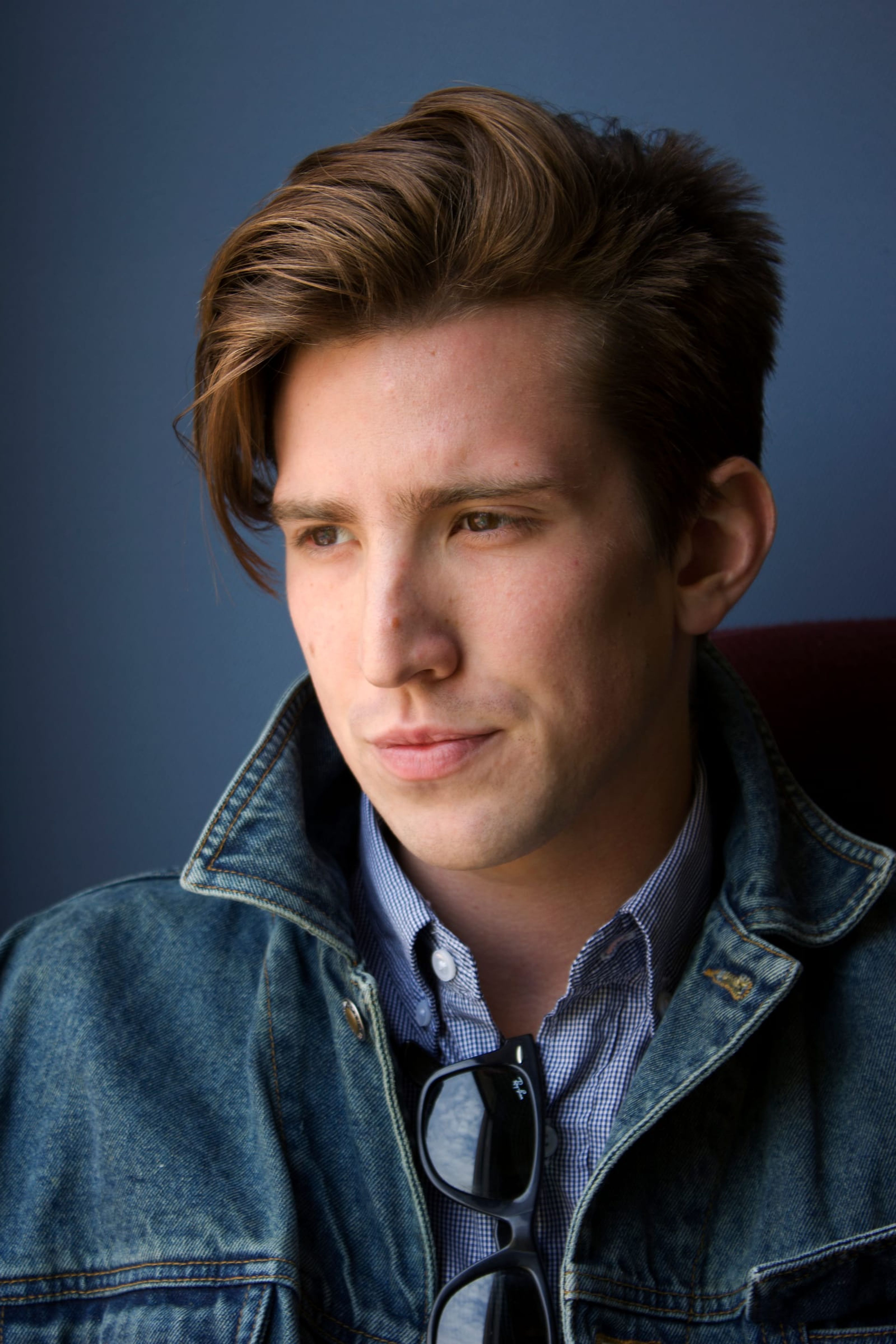 Portrait of Dan in a denim jacket against a blue wall
