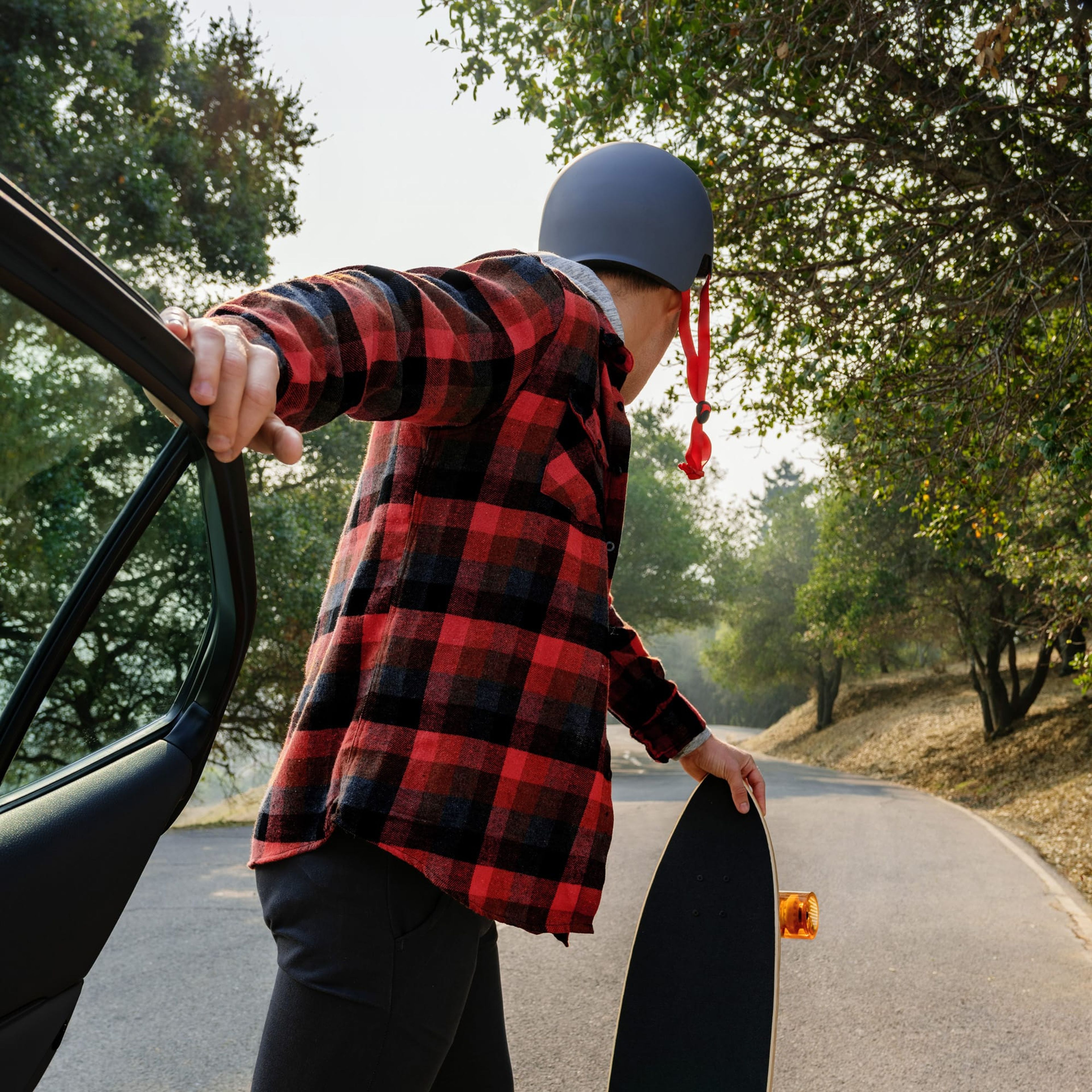Skateboarder in a plaid shirt stepping out of a car