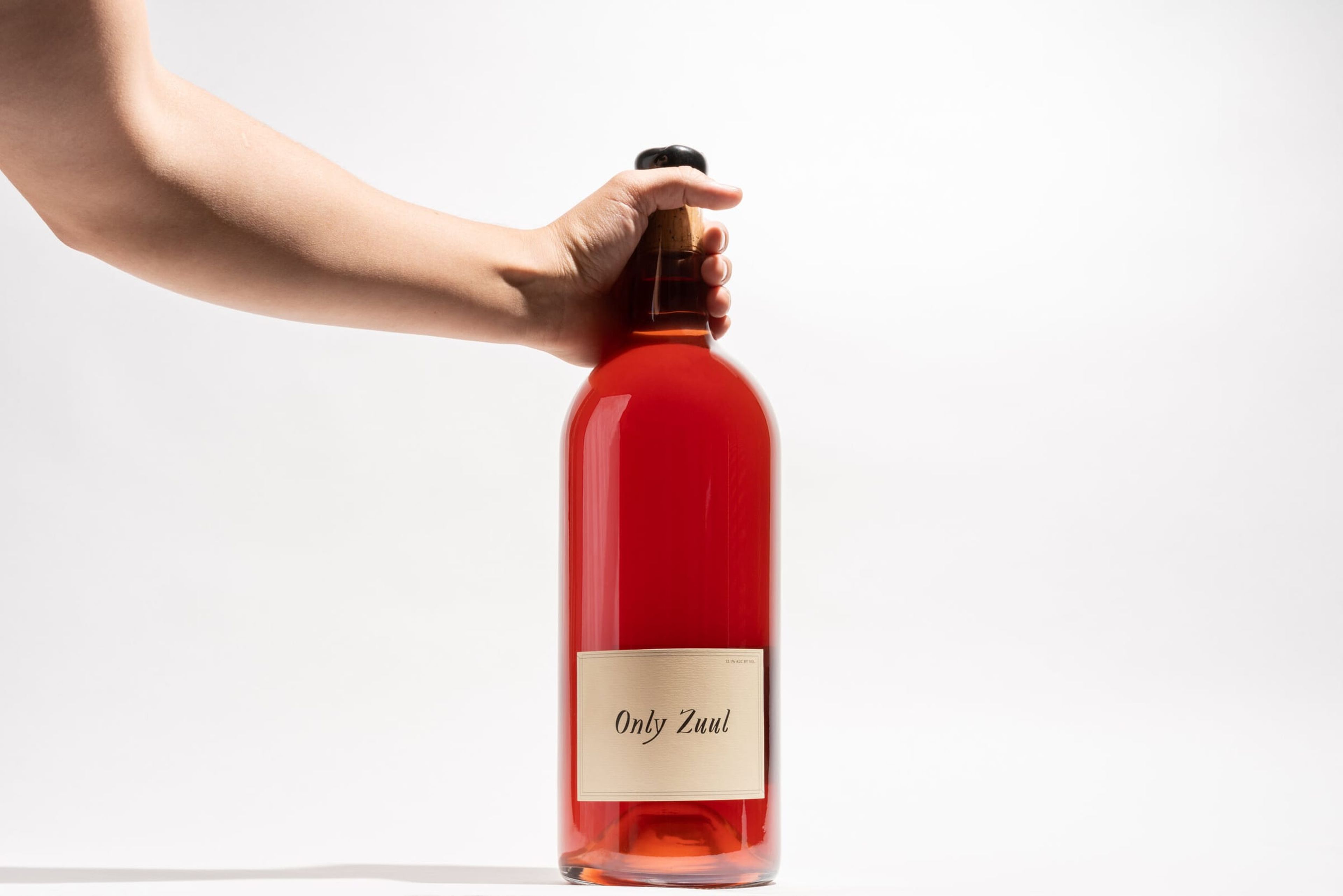 Hand holding a bottle of Only Zuul rosé against white