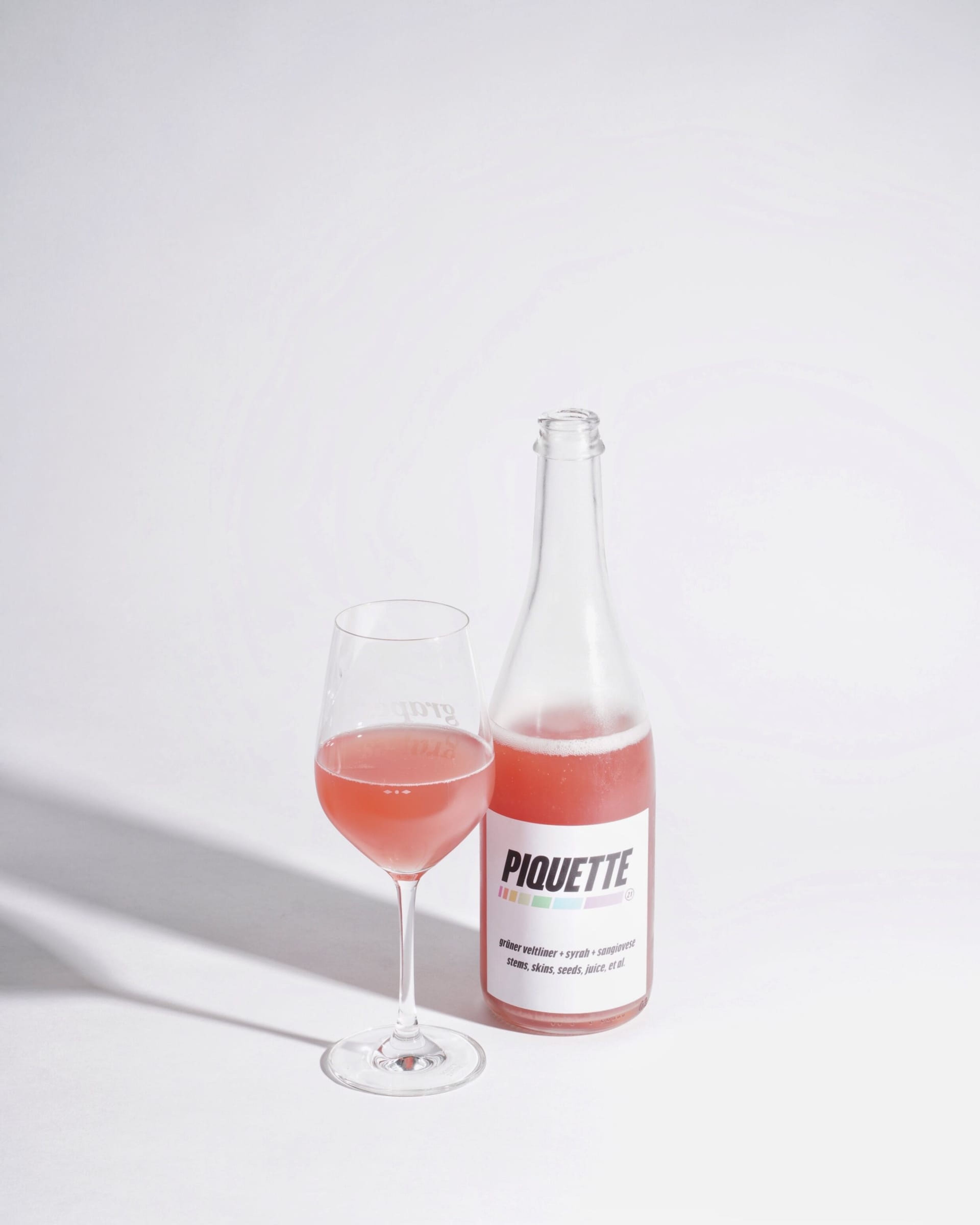 Piquette bottle beside a glass of pink wine