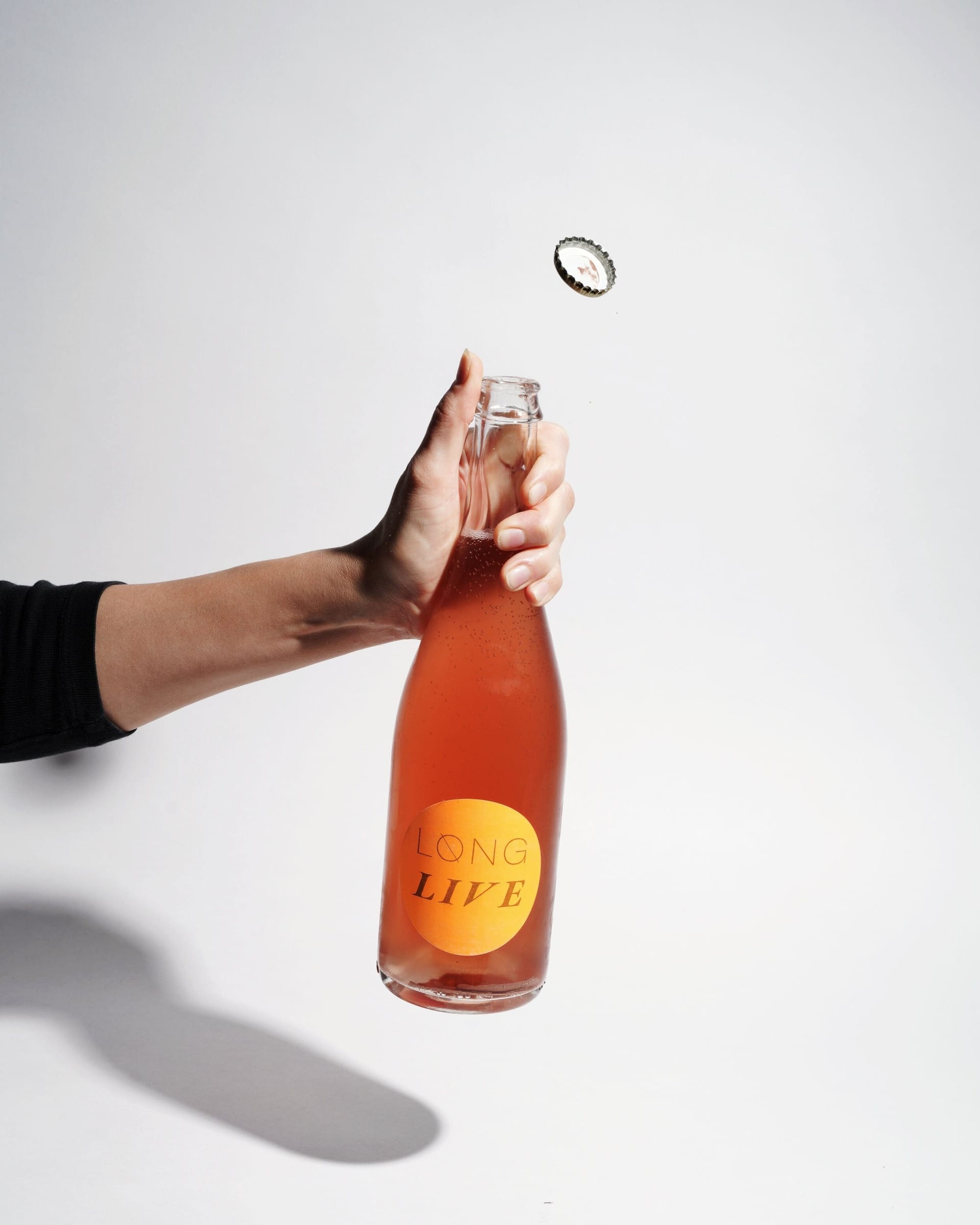 Hand holding a Long Life bottle as its cap flies off