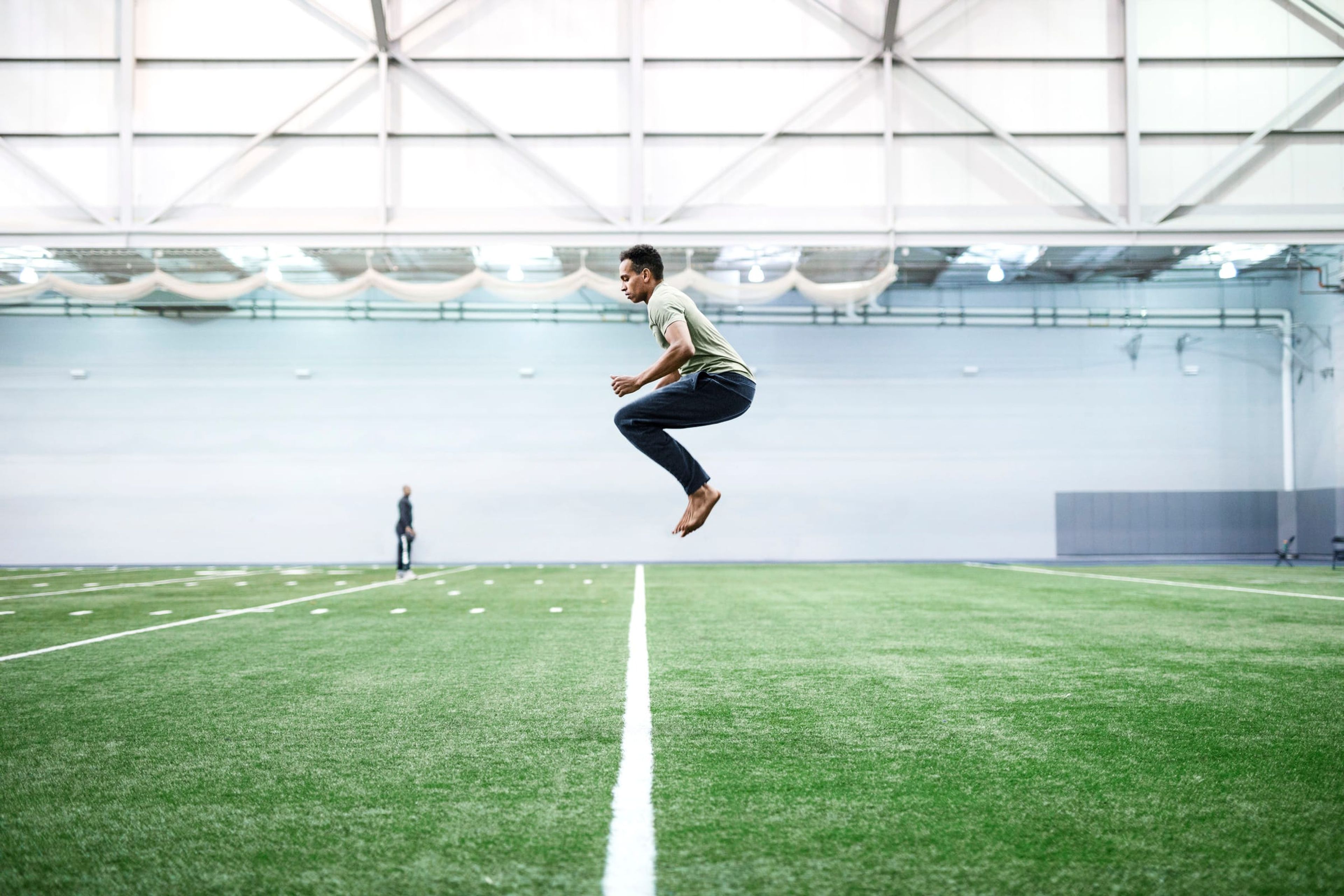 Man leaping mid-air on an indoor football field